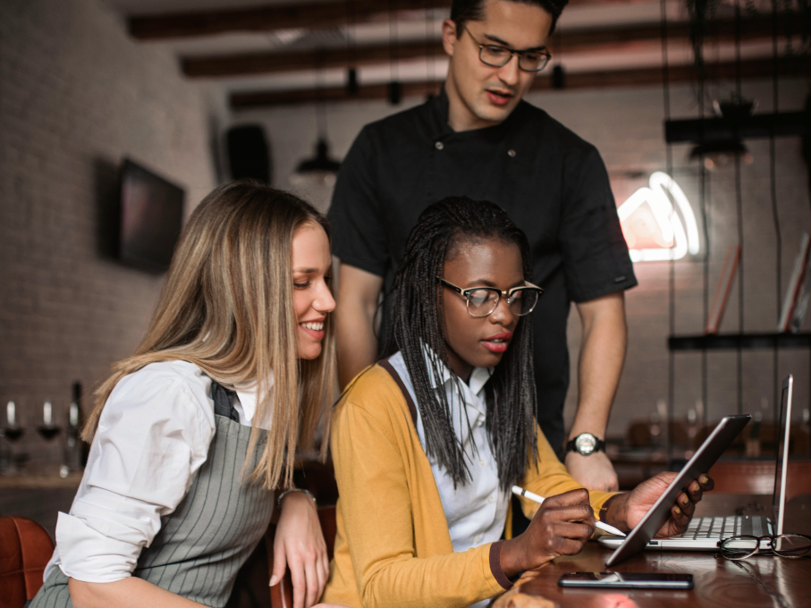 Restaurant manager talking with kitchen staff on laptop and table